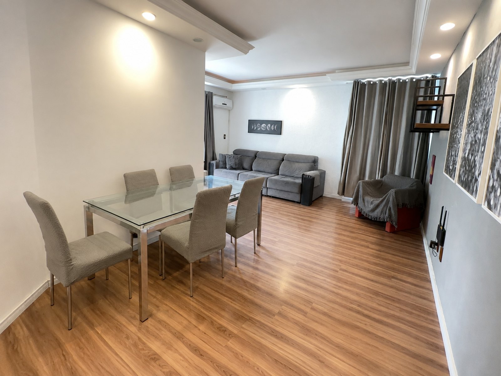 Sala de estar com sofá, mesa de jantar e piso laminado